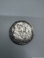 Close-up front view of the 1962 Mexican 25 Peso Centennial Silver Coin showing General Zaragoza on horseback, cannon, and inscription commemorating the Battle of Puebla.