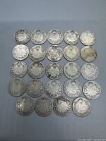 Top view of the obverse side of 24 Canadian 10-cent silver coins laid out in neat rows showing full lot contents with various levels of wear and tarnish.