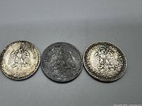 Three 1934 Mexican Un Peso silver coins showing reverse with Mexican coat of arms and inscriptions.