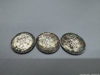 Top side of three 1968 Mexican 25 Peso silver coins showing the Aztec ball player design, Olympic rings, and inscriptions.