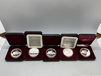 Five 1987 Canadian silver proof dollar coins each in individual protective cases with two Certificates of Authenticity and RCM leather case.