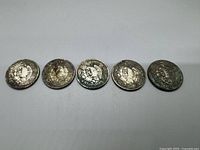 Five Mexican silver one peso coins arranged in a row showing the reverse with the Mexican eagle coat of arms.