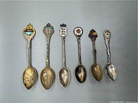 Top view of all six spoons showing enamel decorations and engraved bowls.