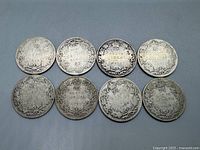 Reverse view of eight Canadian silver quarters showing denomination, crown, and Canadian coat of arms surrounded by maple leaves.