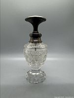 Front view of the perfume bottle showing the hobnail-cut glass body with star-cut base and sterling silver neck and stopper top.