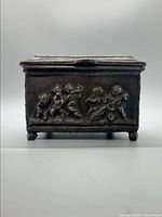 Front view of the metal chest with embossed Viking figures.