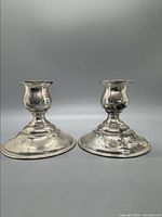 Front view of the pair of silver weighted stick candle holders, showing their shape and wear.