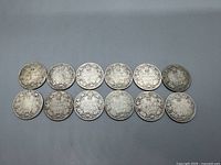 Reverse side of 12 Canadian silver quarters showing Canadian coat of arms, condition worn with patina and tarnish.