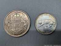Two Canadian silver coins, 1957 half dollar and 1967 quarter, front side showing emblem and bobcat with inscriptions