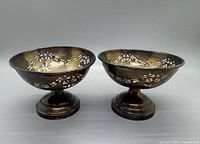 Pair of sterling silver weighted dishes shown from front, displaying round form and pierced decorative pattern.