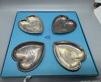 Four heart shaped silver-tone nut dishes in a blue Birks box, showing used condition with tarnish and wear.