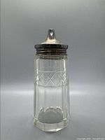 Full view of the cut glass serving jar with silver lid indicating overall condition and design