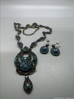 Photo showing necklace and earrings laid flat to show details and stones.