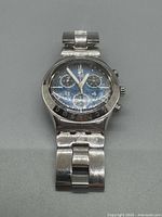 Front view of the Swatch Irony Chronograph watch showing black dial, subdials, and stainless steel bracelet.