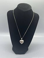 Full view of sterling silver heart necklace with locket displayed on black necklace bust
