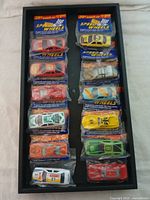 Top view of all 12 Speed Wheels cars in original sealed packaging arranged inside a black display case.