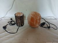 Two salt lamps side by side on a white surface with electrical cords and switches visible
