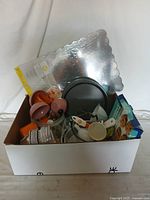 Photo of the box showing a variety of baking items including silicone bowls, baking pans, disposable aluminum cups, measuring cups, and cookie mix box.