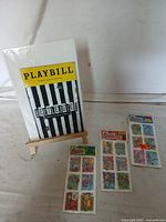 Full view of the Beetlejuice Playbill and three-pack vintage Beetlejuice stickers displayed on a small wooden easel and laid out next to it.