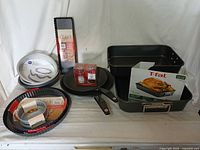 Full view of all cooking pans and bakeware spread out showing the variety including roasting pans, cake pans, tart pans, frying pan with lid