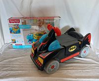 Batman Wheelies Batmobile toddler ride-on car in black with red and blue accents and Batman logo, including wheels and play ramp with sound feature.