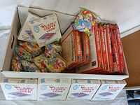 Wide shot of box containing multiple Colonial Hi-Lo Looper Looms, five red weaving loom boxes, and bags of yarn strips.