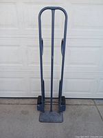 Front view of full metal dolly showing tall frame, handles, and wide base.