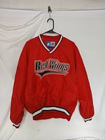 Front view of red Red Wings NHL Starter jacket with logo on chest and elastic cuffs and waistband.