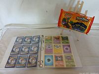 White binder opened showing sleeved Pokémon cards including various basic Pokémon such as Ponyta and Weepinbell