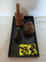 Full view of three large wooden hand sculptures including middle finger, fist, and thumbs-up, with several small miniature wooden hands scattered in front.