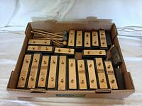 Box with assorted wooden xylophone keys on black bases, arranged neatly and labeled by note.
