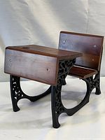 Front angled view of the mini school desk showing cast iron legs with scrollwork and wooden bench attached