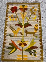 Full view of the vintage handwoven kilim showing complete pictorial design with birds, fox, flowers, and foliage in earth tones against beige background.