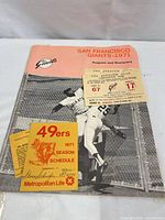 The main program and scorecard with two tickets and 49ers season schedule laid on a surface, showing the program cover and accompanying items.