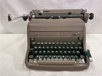Front view showing the full keyboard layout with dark green keys and the brown body casing, main typewriter carriage visible.