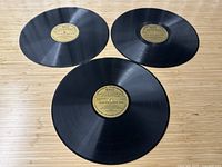 Three 12-inch black vinyl records on wooden surface, showing condition and overall appearance.