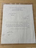 Full view of the typed Hebrew letter sheet in protective sleeve on woodgrain surface