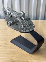 Side angle view showing pewter Millennium Falcon on black curved stand