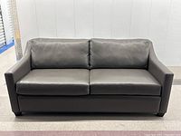 Front view of the grey leather sofa showing full length and cushion arrangement