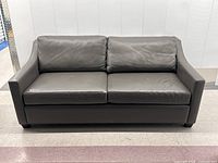 Full front view of grey leather sofa showing overall shape and color