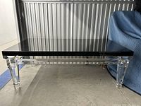 Full front view of coffee table showing black marble top and clear lucite base