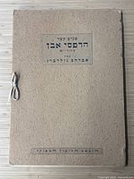 Textured ingrain cardboard portfolio cover with Hebrew title and original ribbon tie