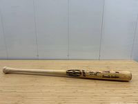 Full-length view of 34-inch bat on wooden surface showing natural wood finish and knob.