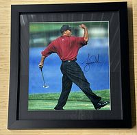 Front view of framed signed photograph showing Tiger Woods in red shirt fist pumping
