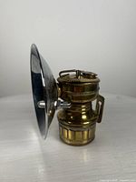 Side profile of brass miner's carbide lamp showing water and carbide chambers, with reflector bowl attached.