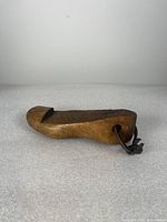 Side view of antique wooden shoe form showing its profile and metal loop.