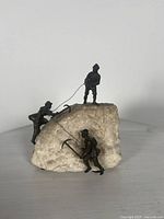 Front view of sculpture showing all three climber figures on stone base