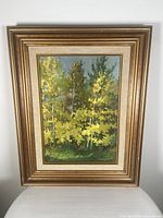 Full frontal view of the painting and frame showing vibrant yellow-green autumn trees in a forest scene. The gold and beige frame is ornate and textured.