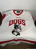 White Bauer XL sports shirt with "DOGS" and fierce dog logo on front, red trim on collar and sleeves.