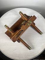 Top and angled side view of the wooden sash fillister plane with brass fittings and two wooden handles capped with brass.